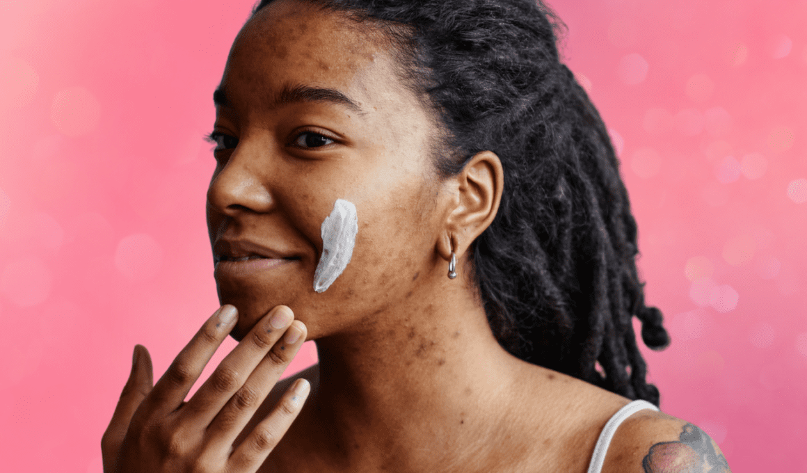 Woman with hyperpigmentation from acne applies swipe of cream to her cheek