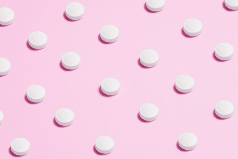 Spironolactone: small white pills arranged in diagonal lines on a pink background