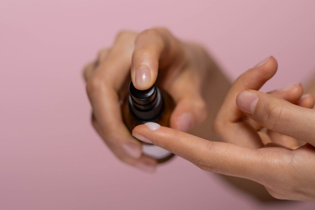 Azelaic acid for acne: close up of hand dispensing skin care product onto finger with a pink background