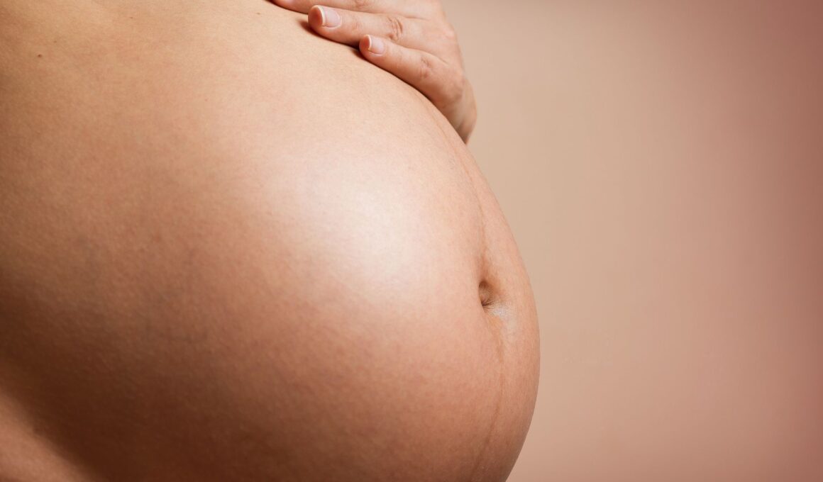Pregnancy acne: Pregnant stomach with a hand laid across the top