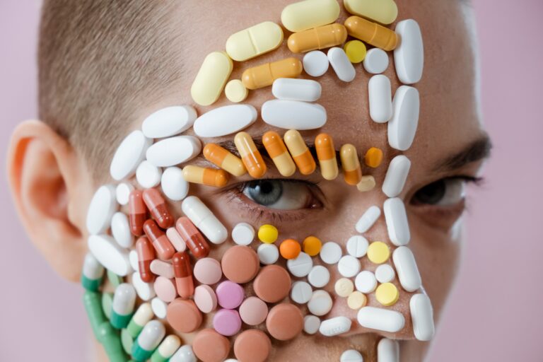 Accutane: person with variety of pills of different colors and shapes stuck on their face.