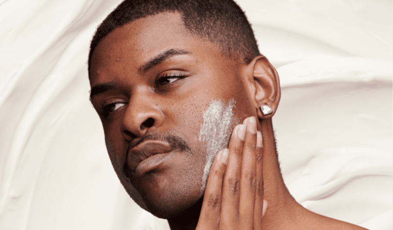 Man with mild acne practices face basting by applying thick white cream to face