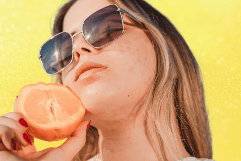 Woman with acne holding half an orange to her face