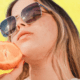 Woman with acne holding half an orange to her face